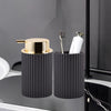 A black foaming soap dispenser with a gold pump and a toothbrush holder is shown on a kitchen sink.