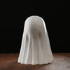 A smooth, white ghost statue decoration is shown from the back against a dark background.