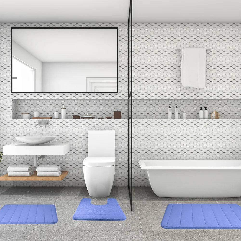 Weiβes Badezimmer mit Toilette, Waschbereich und Badewanne, bedeckt von drei blauen Schaumstoff-Badematten.