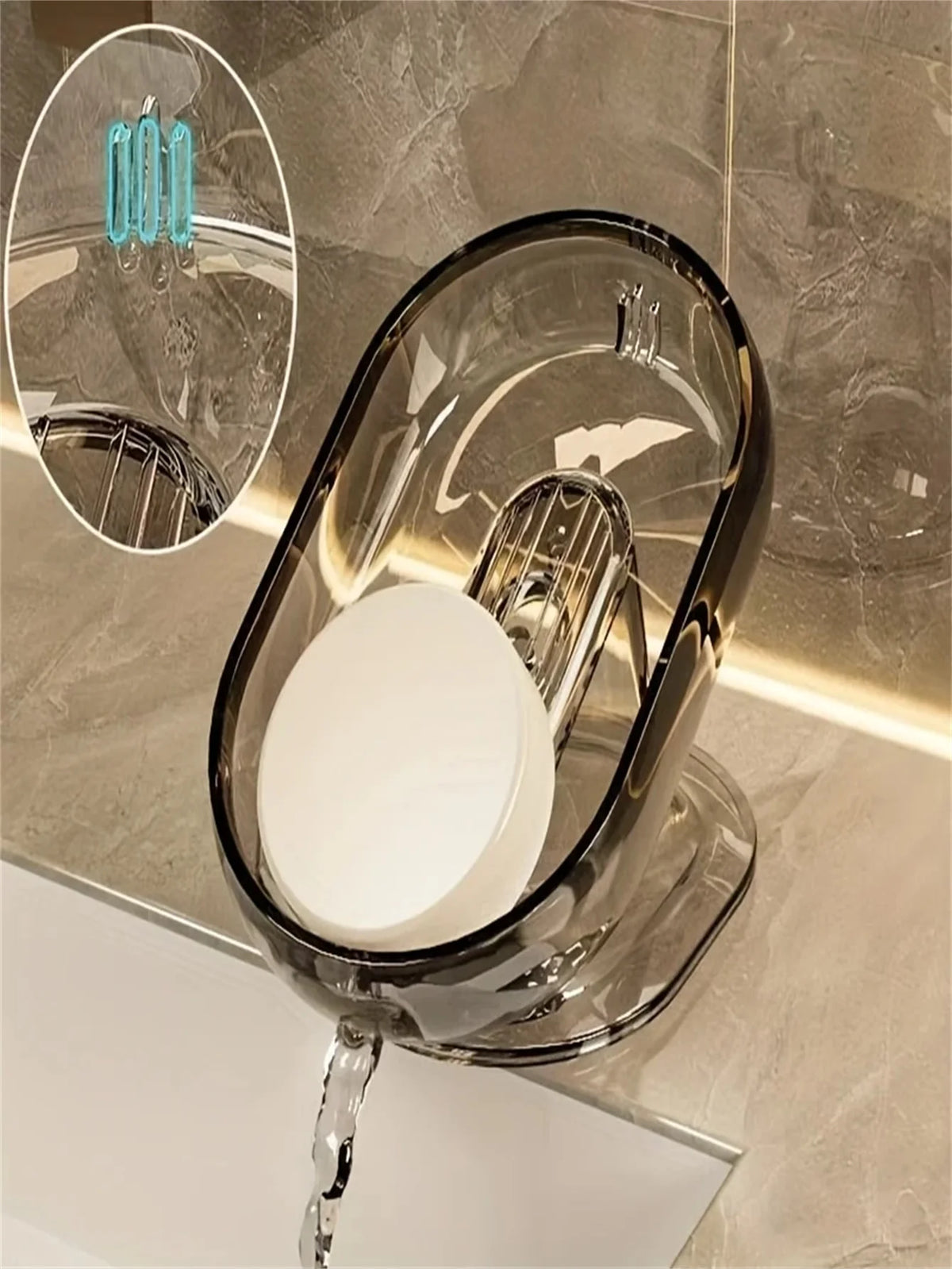 A clear glass soap dish with a metal drainer is displayed on a marble countertop.