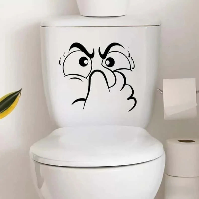 A white toilet featuring a black cartoon face decal with wide eyes and furrowed brows.