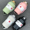 Three stainless steel insulated tumblers in green, pink, and black are displayed on a gray surface.