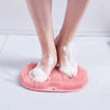 Un par de pies descalzos descansando sobre una estera de ducha de masaje de silicona rosa con espuma blanca.