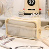 A beige transparent pencil pouch is displayed on a white surface next to a yellow appliance and other stationery.