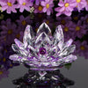 A clear crystal lotus flower tabletop decor with a purple gemstone center resting on a reflective base.