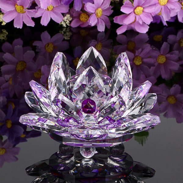 A clear crystal lotus flower tabletop decor with a purple gemstone center resting on a reflective base.