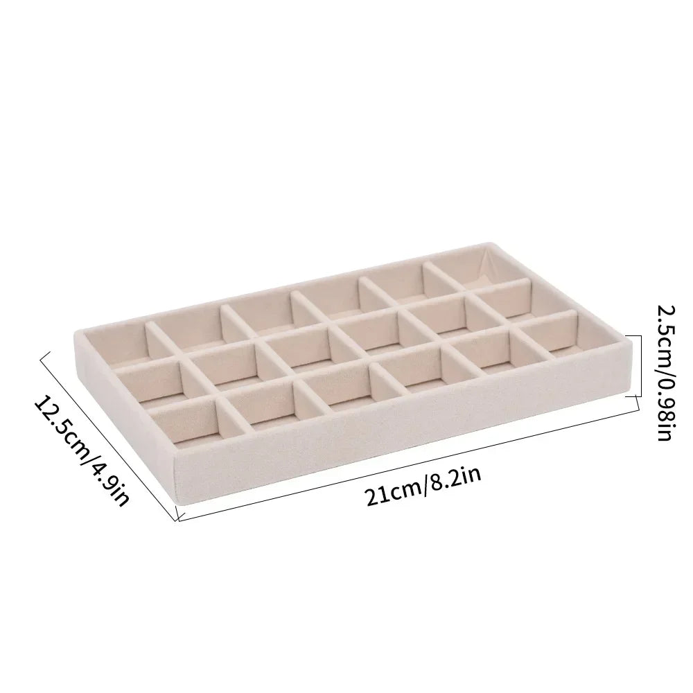 A rectangular velvet jewelry organizer tray with a soft lining, featuring a grid pattern for storing items.