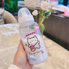 A hand holds a clear water bottle with a cute pink strawberry bear design on it.