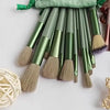 A set of luxury vegan makeup brushes with green handles and natural hair bristles displayed against a light background.