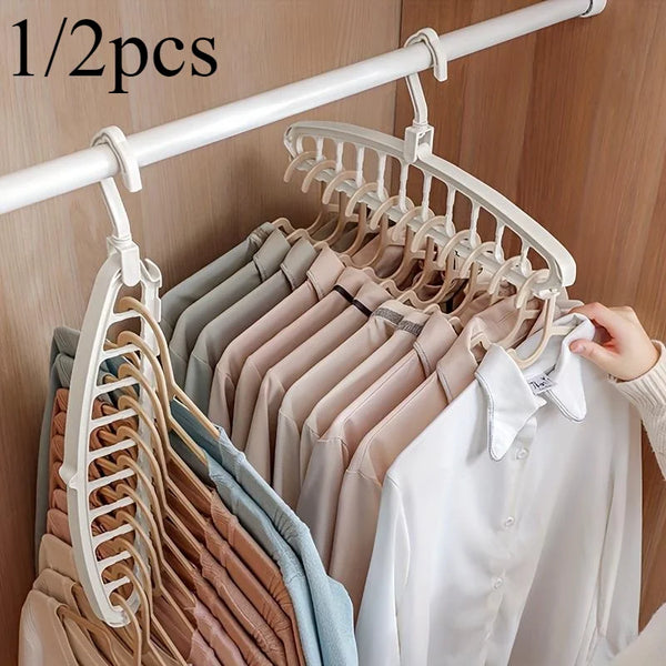 A white laundry drying rack with multiple hangers is displayed on a wooden rod, showing various colored shirts and blouses.