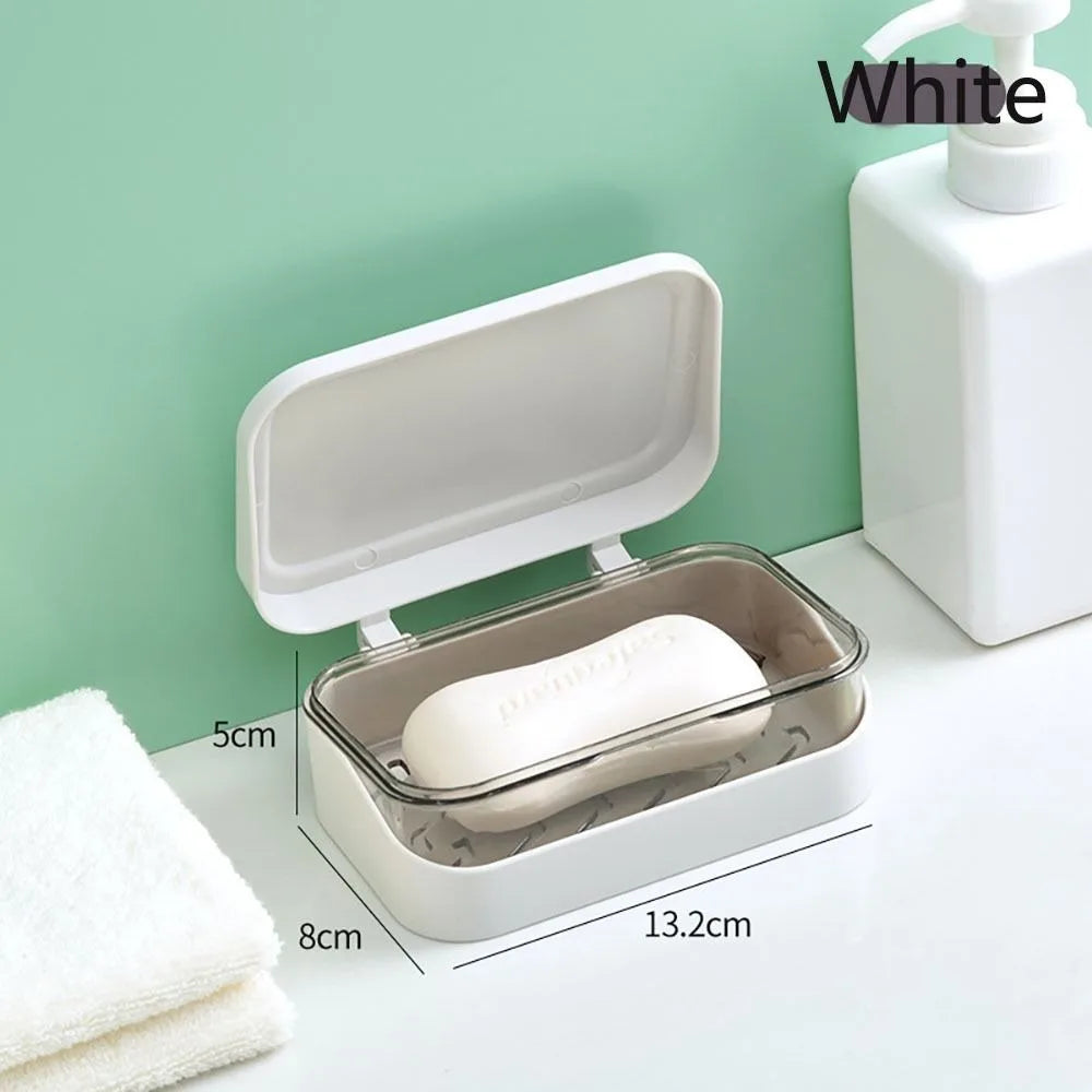 A white transparent drainage soap dish with a lid and a bar of soap is shown on a white surface.