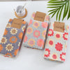 A set of three textured kitchen cleaning cloths in floral patterns with jute tags on a white surface.