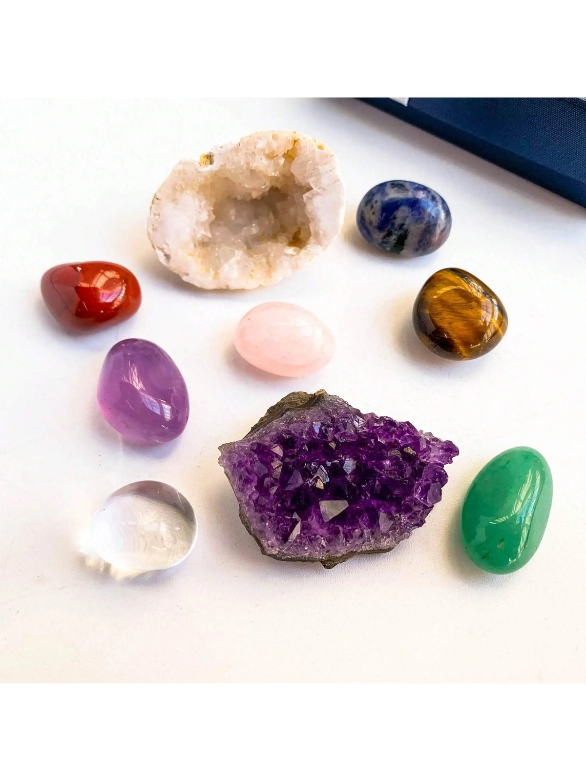 A collection of natural crystals including amethyst, citrine, blue sapphire, rose quartz, and green jade stones.