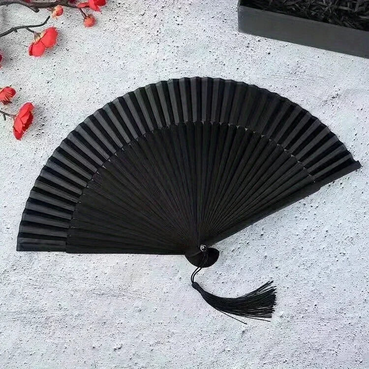 A black vintage bamboo folding fan is displayed against a white textured background.