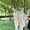 A close-up of a white clothesline with hangers displaying various light-colored garments hanging outdoors.