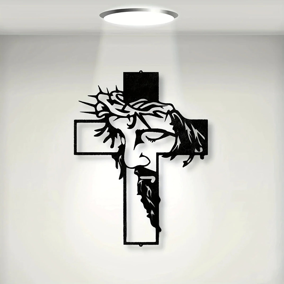 A black metal cross wall art featuring a carved face and beard design, illuminated by a spotlight.