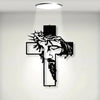 A black metal cross wall art featuring a carved face and beard design, illuminated by a spotlight.