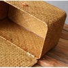 A close-up view of a handwoven rattan storage basket with a lid resting on a wooden surface.