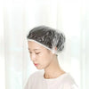A woman is wearing a disposable shower cap while looking down, demonstrating the product for hair protection.