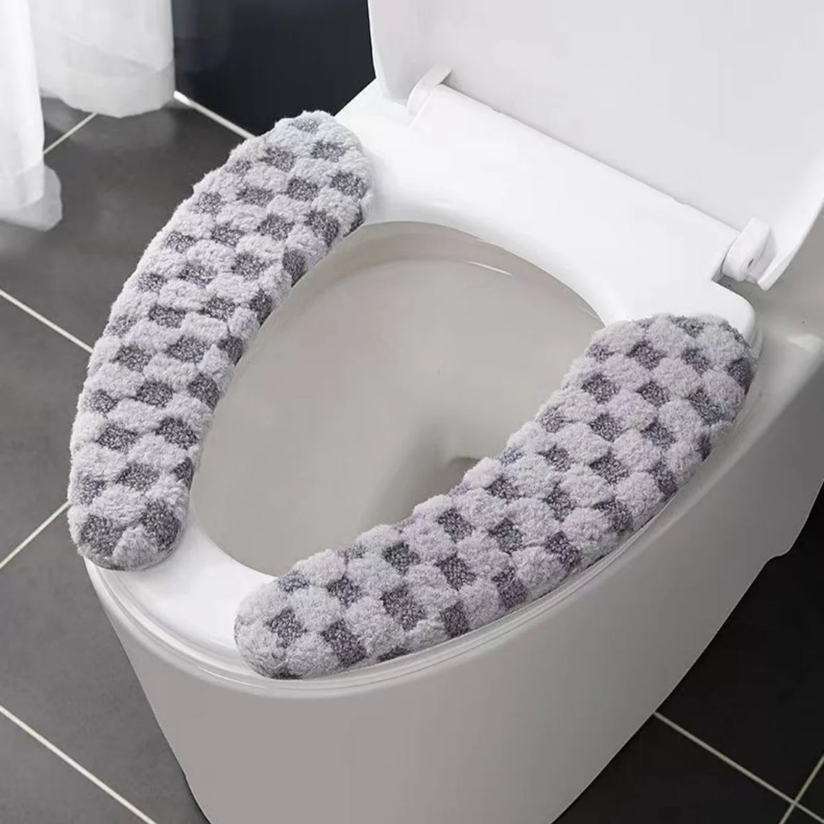 A toilet seat cushion cover with a gray and white patterned fabric is shown inside a white toilet bowl.
