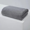 A gray textured bath towel folded neatly on a white surface.