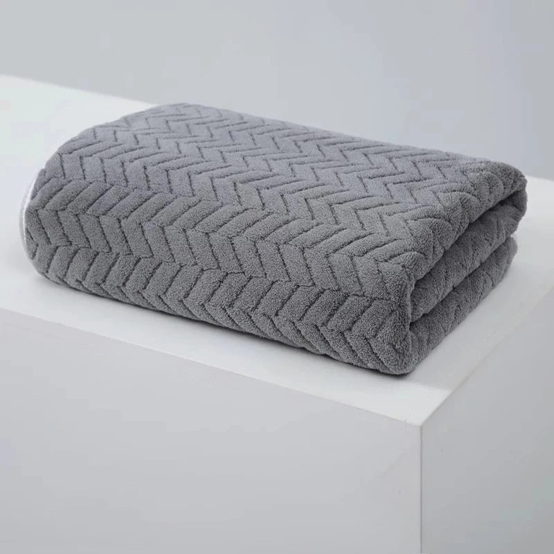 A gray textured bath towel folded neatly on a white surface.