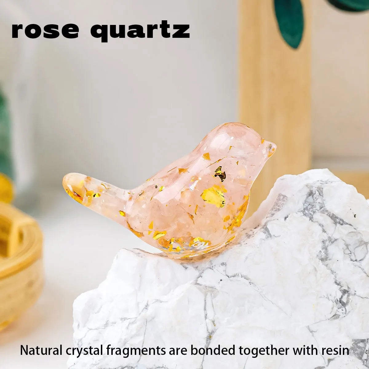 A pink rose quartz crystal bird statue resting on a white marble surface.