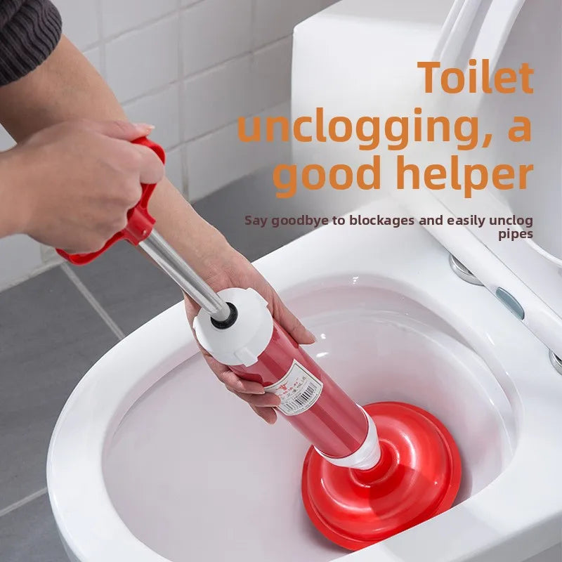 A hand is using a red heavy-duty toilet plunger to unclog a toilet drain.