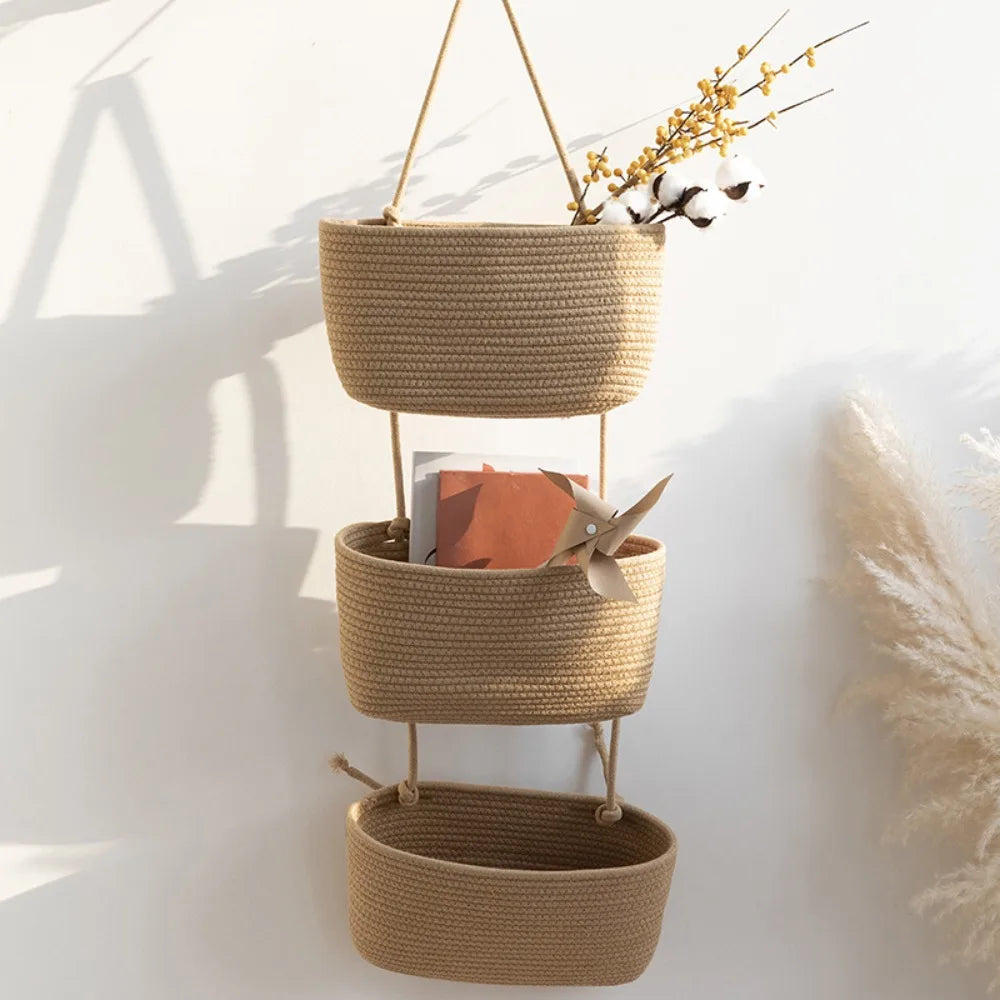 Handwoven multi-layer wall storage baskets in natural beige fiber hanging against a white wall.