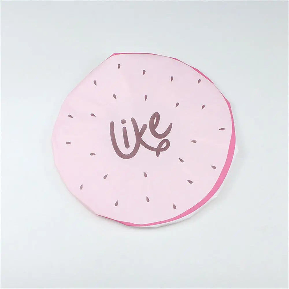 A pink reusable fruit shower cap with a stylized cursive word like on it.