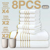 A set of eight white square bath towels stacked and displayed with a wooden brush.