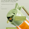 A close-up of a green oil spray bottle demonstrating an anti-drip design and an automatic oil suction nozzle.