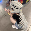 A person wearing a gray dinosaur skeleton costume with large teeth and a tail, posing on a tiled floor.