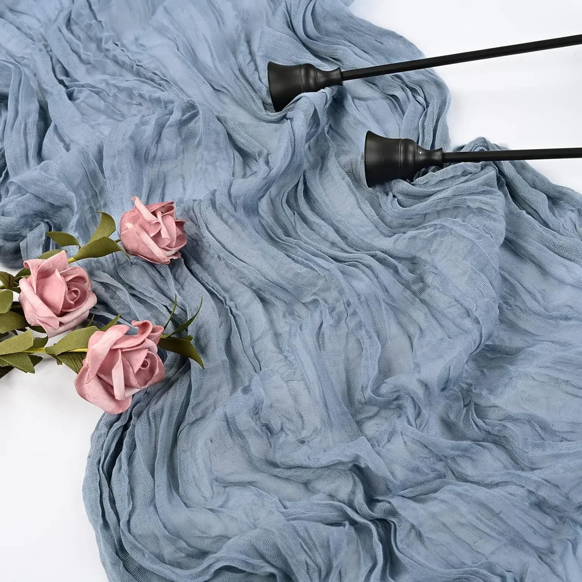 A light blue fabric runner with dark-colored decorative elements and pink roses.
