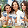 Four women holding blue glass champagne flutes in a bright indoor setting