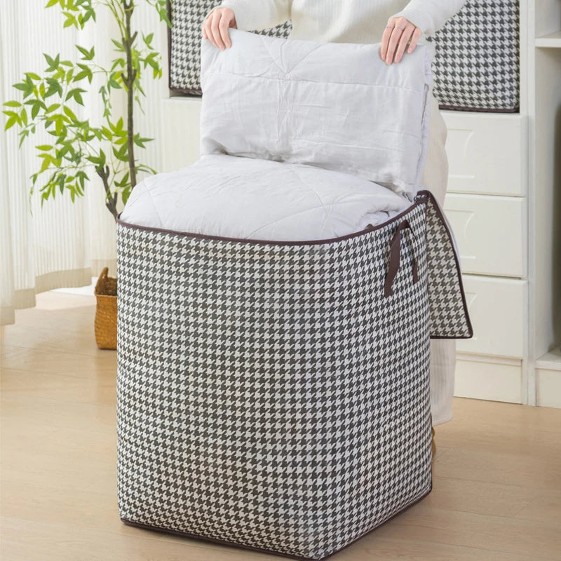 A foldable clothing storage bag with a black and white houndstooth pattern is shown next to a white pillow.