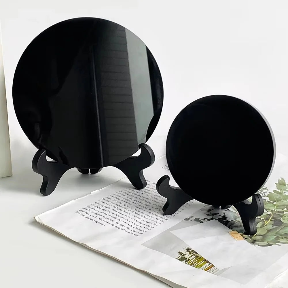A black obsidian scrying mirror decor is shown resting on a piece of paper.