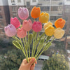 Un bouquet de fleurs de carnation en coton faites à la main, dans des tons de rose et d'orange.