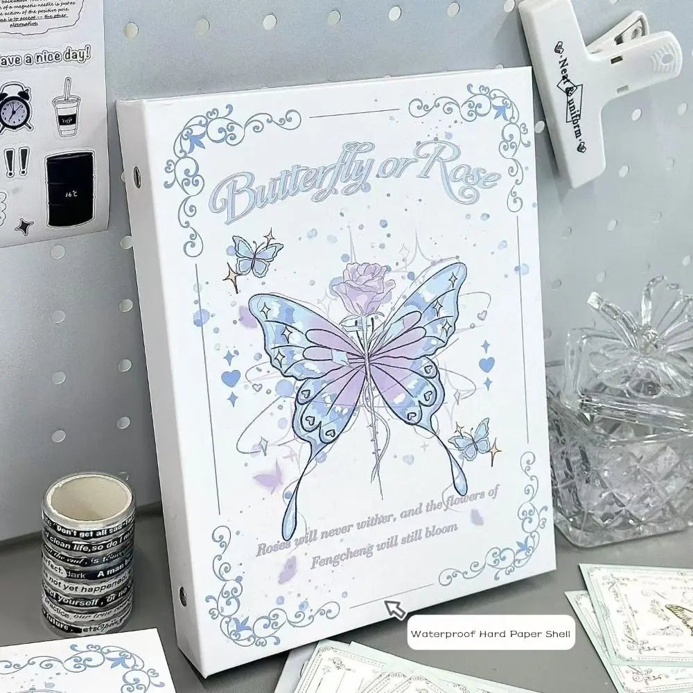 A white photo album featuring a butterfly and rose design on the cover, displayed next to a clear glass and a white plastic i