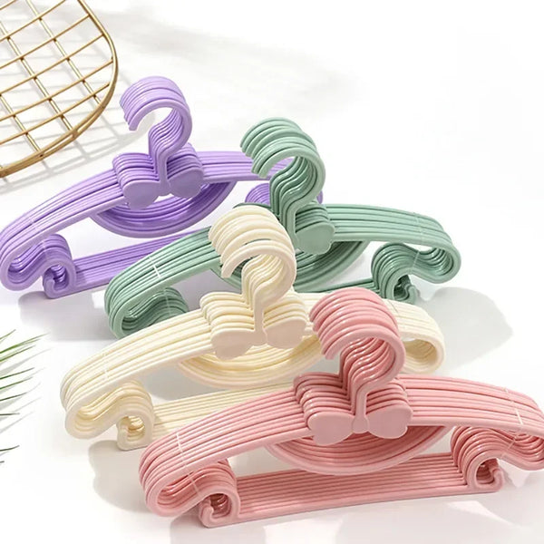 A collection of adjustable non-slip clothes hangers in various pastel colors including purple, mint green, cream, and pink.