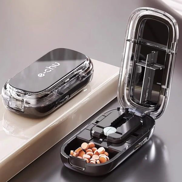 A portable pill cutter and organizer set with a clear plastic case and an inner compartment holding pills.