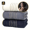 A stack of three dark blue bath towels with gold stripes, including a circular inset showing a towel on a person.