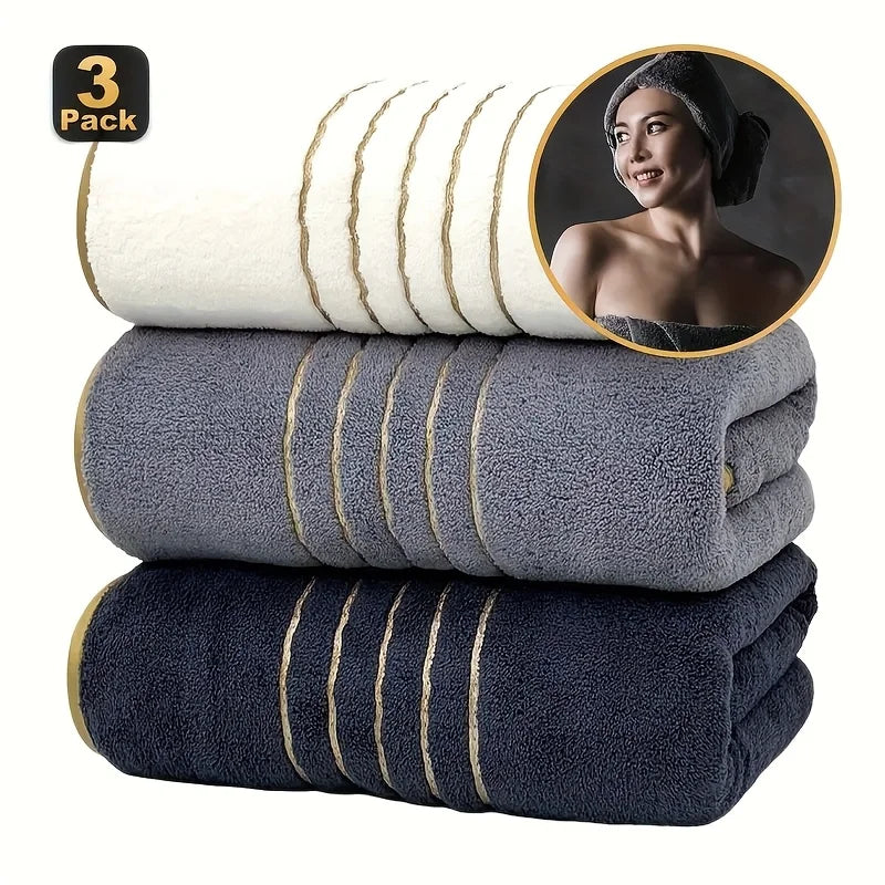 A stack of three dark blue bath towels with gold stripes, including a circular inset showing a towel on a person.