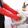 A person wearing red silicone dishwashing gloves is washing dishes in a stainless steel sink.