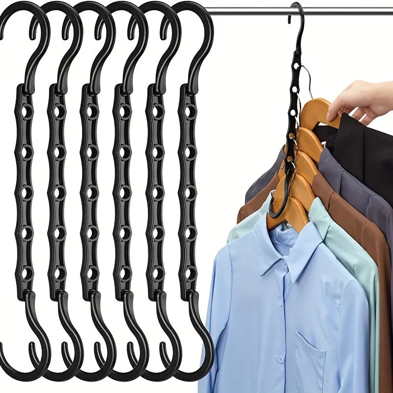 A multi-pack of black plastic clothes hangers hanging on a wire, with several shirts displayed below.
