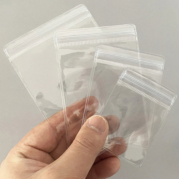 A hand holds a clear PVC zip lock jewelry pouch, showing the transparent plastic packaging.