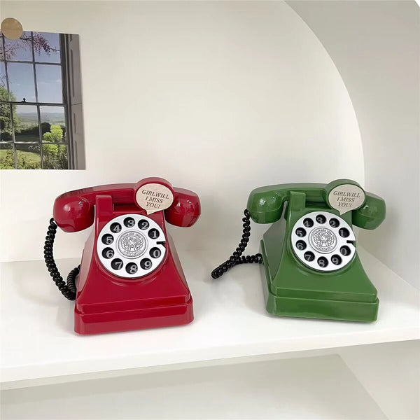 A vintage red and green retro telephone set displayed on a white shelf.