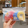 A hand holds a clear plastic storage bag filled with colorful frosting or candy in the shape of daisies.