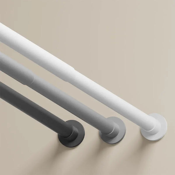 A close-up view of a silver shower curtain rod with a round mounting plate against a beige wall.