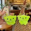 A pair of bright lime green Galaxy Cat plush keychains hanging from a brown woven bag.